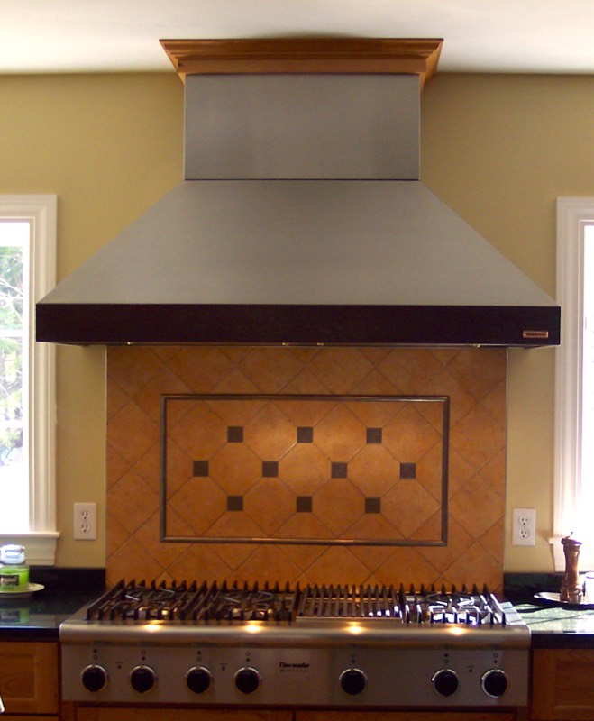 Terracotta tile backsplash with an inset diamond pattern behind a range hood