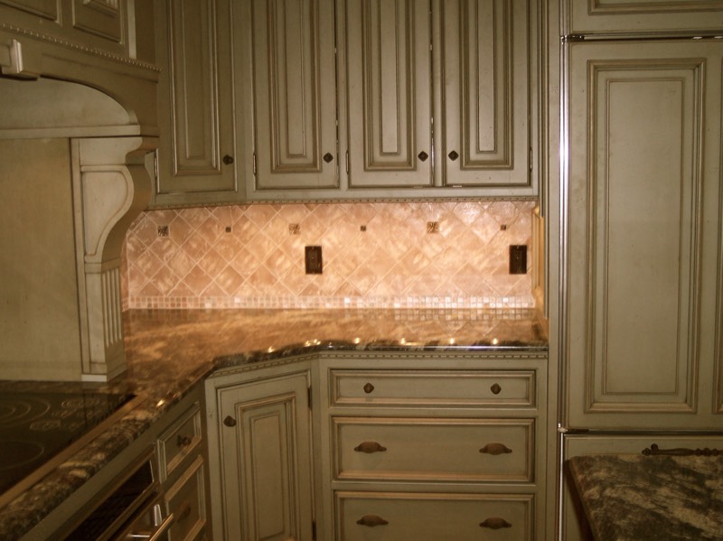 Tumbled stone backsplash with a glass mosaic accent stripe
