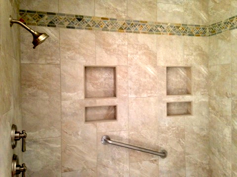 Tiled shower with recessed niches and a decorative mosaic border